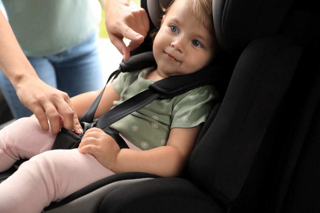 Woman fastening a child safety seat inside a car